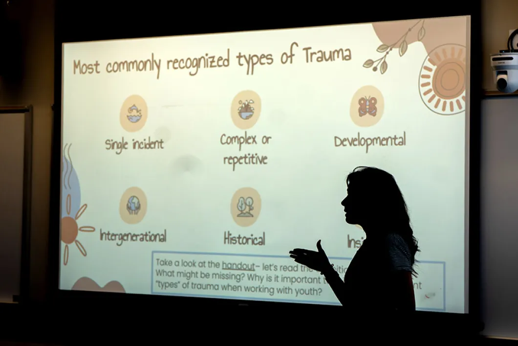 A person standing in front of a projection showing a slide that refers to trauma