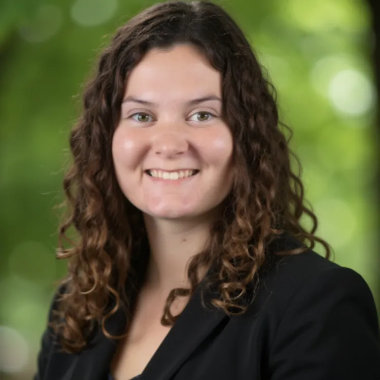 A smiling young woman with curly brown hair. 