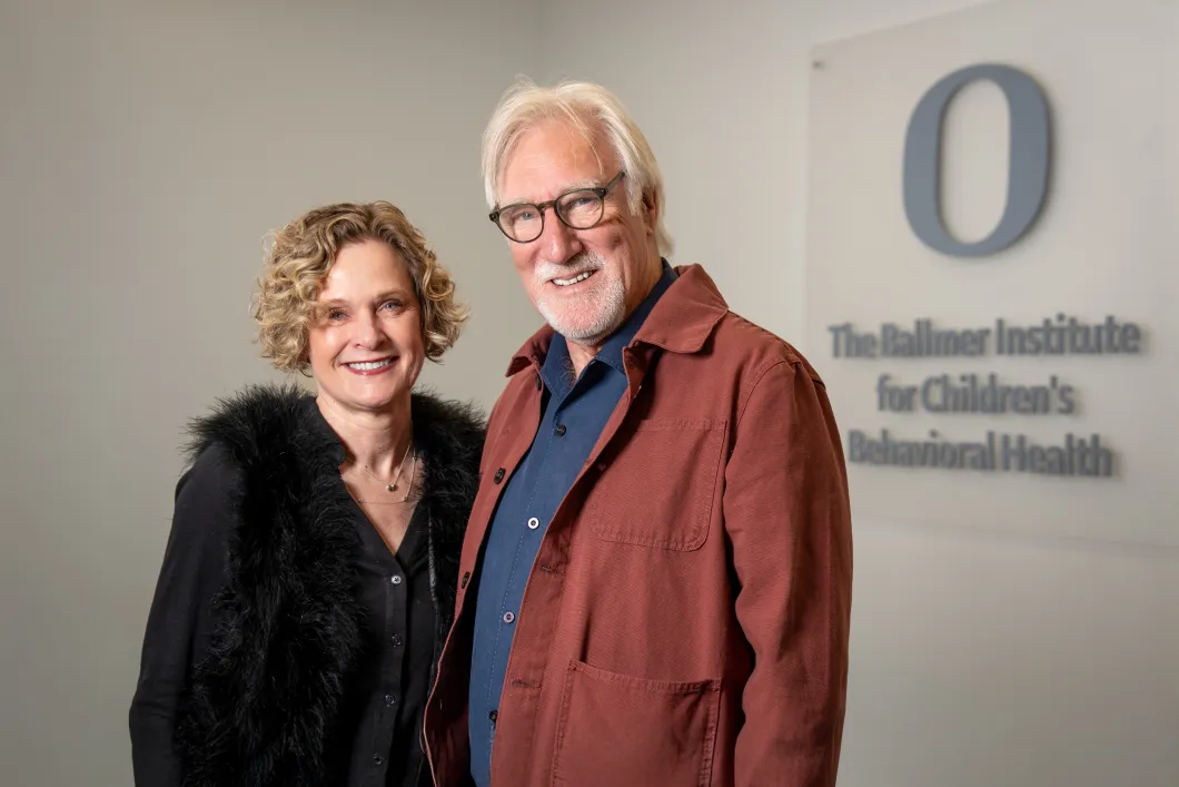 Lisa Redekop and Les Kaski standing together smiling at the camrea with the Ballmer Institute for Childern's Behavioral Health sign behind them
