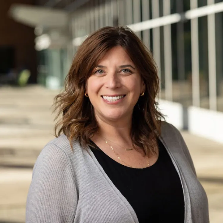 A woman with wavy brown hair smiles. 