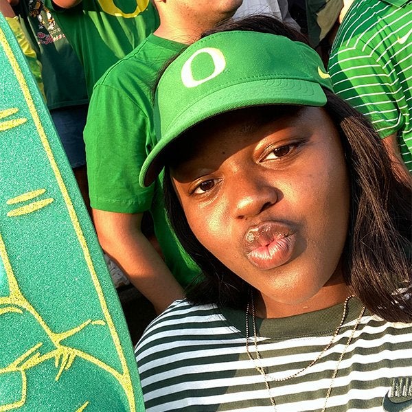 Student in a Ducks cap and green foam finger