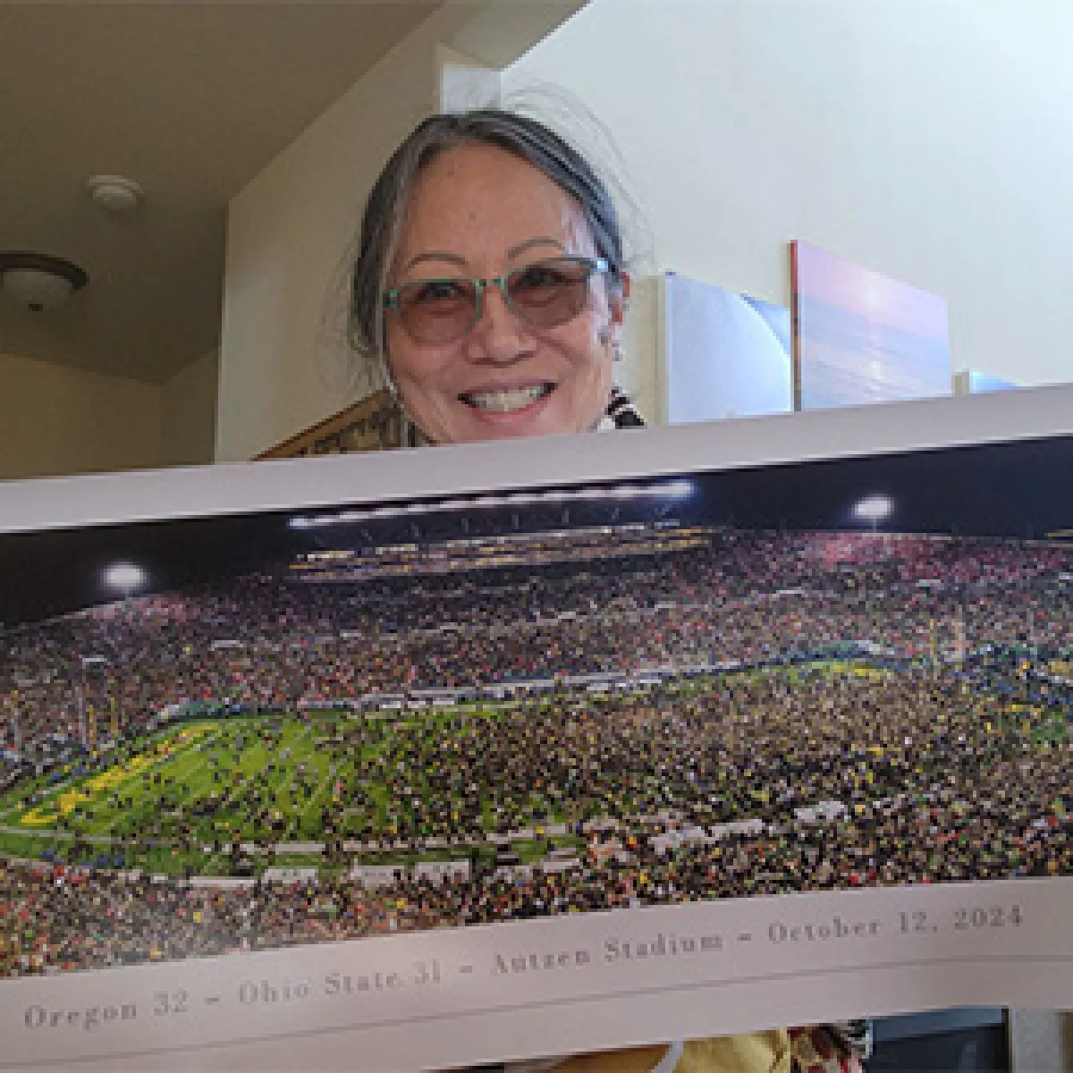 Woman holding poster of a football game at Autzen Stadium
