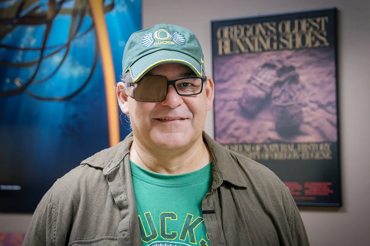 David Lewis poses in front of a poster of the world's oldest shoes
