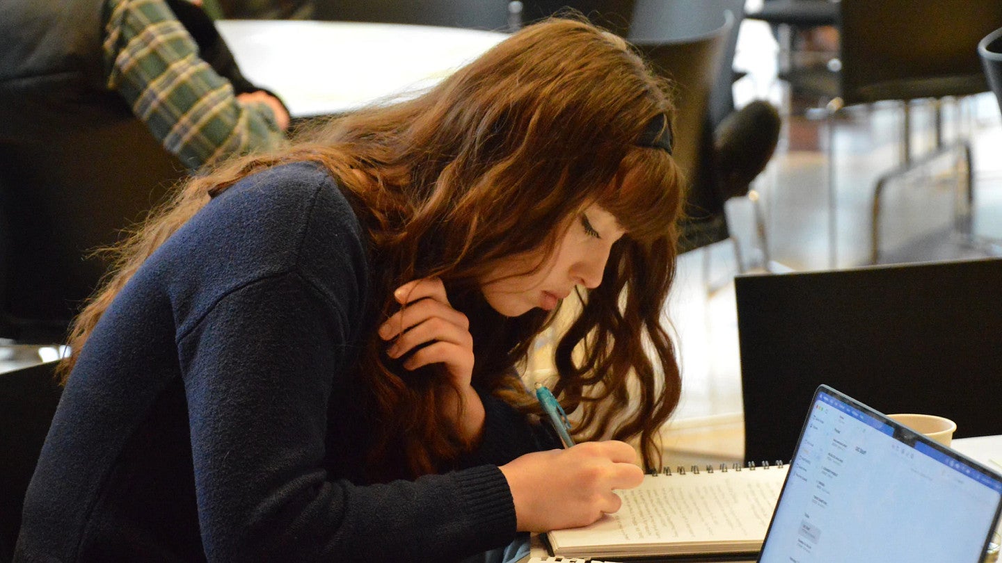 Graduate student writing in a notebook.