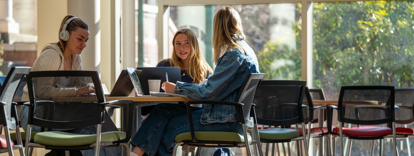 Three students study at a table together.