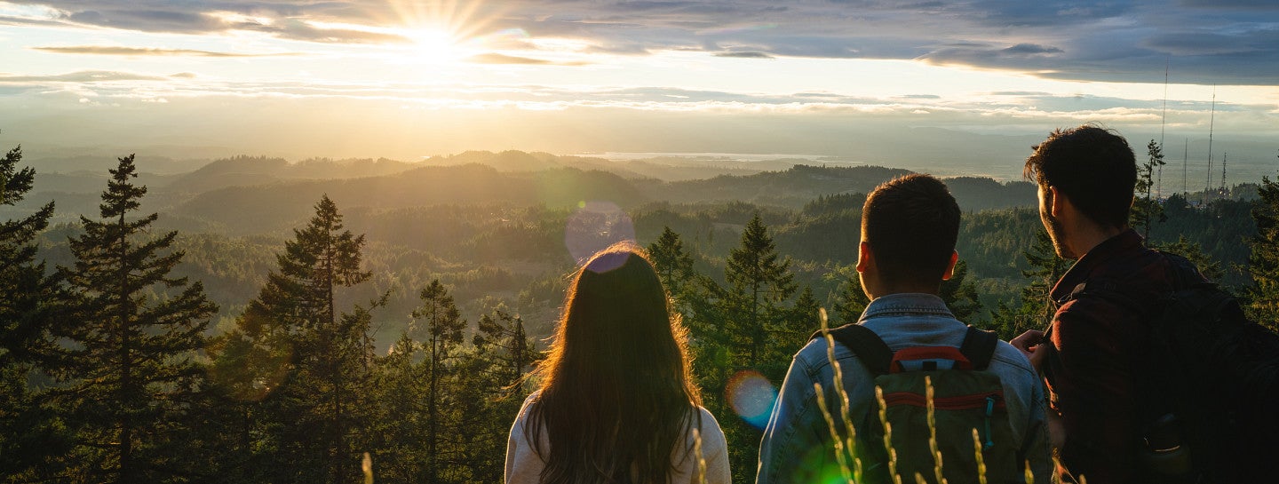 Three students watch the sunrise.