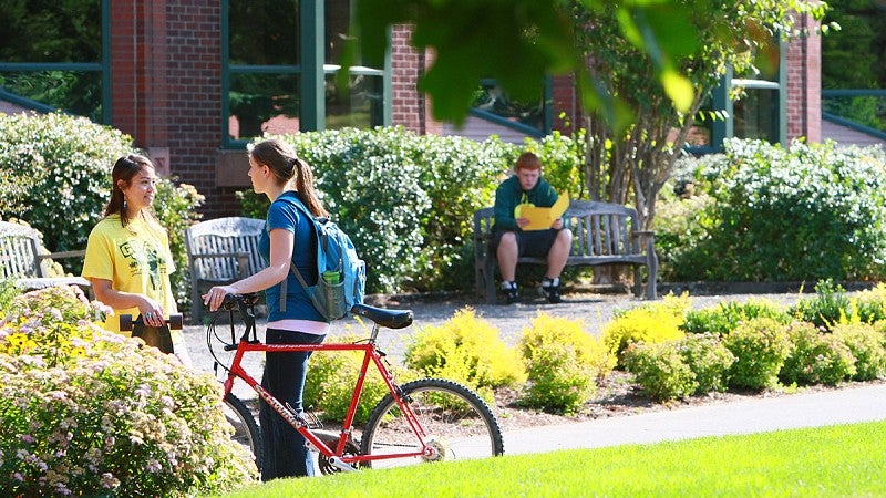 two students with bikes talking outside 