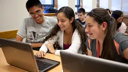 three students working on laptop