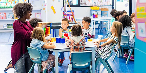 Teacher working with three small children in a classroom