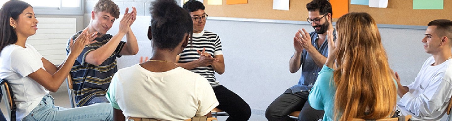 A group of high school students sitting in a circle with their teacher and having a discussion