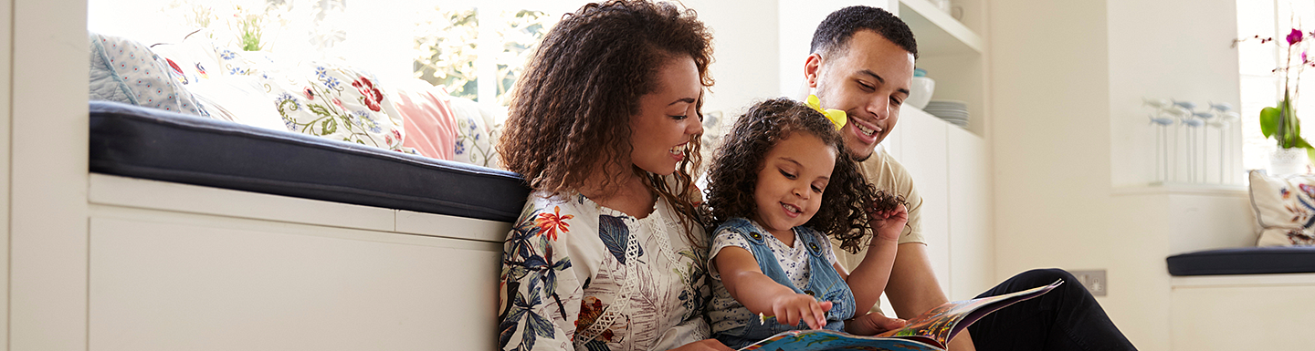 Parents reading to their young daughter 