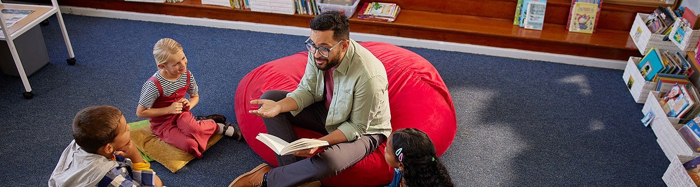 A teacher reading to a group of elementary students 