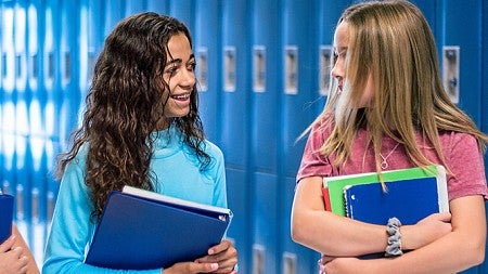 Three high school students walking in the hall and talking happily 