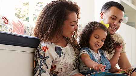 Parents reading to their young daughter 
