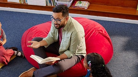 A teacher reading to a group of elementary students 