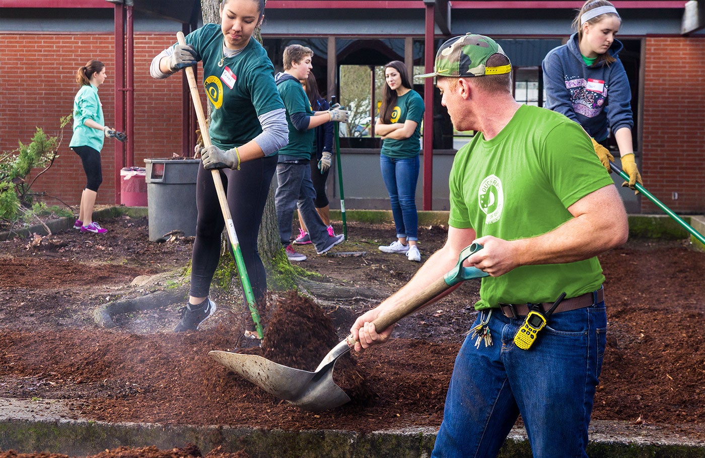 Students and staff shoveling fresh bark.