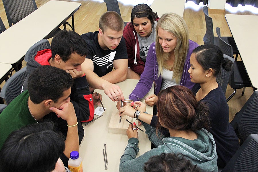 Students working together to build a house out of nails.