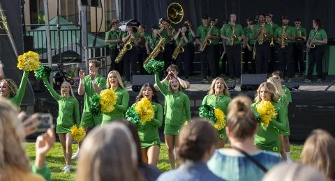 Cheerleaders wave their green and yellow pom-poms