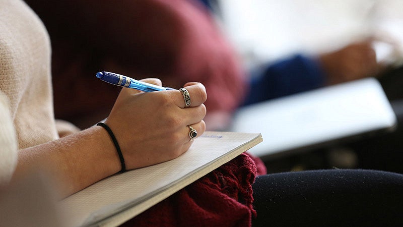 (Person writing notes by hand in a notebook.) English Minor