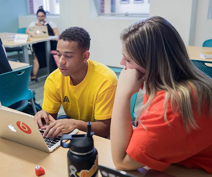 Students seated at computers, with two in the foreground focused on Real World Experience work.