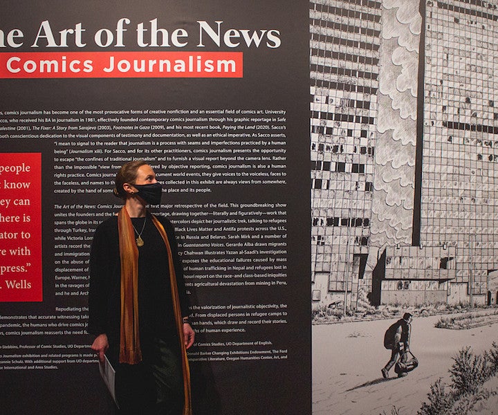 Person standing in front of a Comics Journalism wall display.