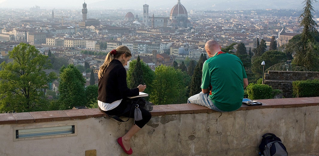 (Two students are sitting and sketching or writing at sunset in Siena, Italy.) Creative Writing in Oviedo