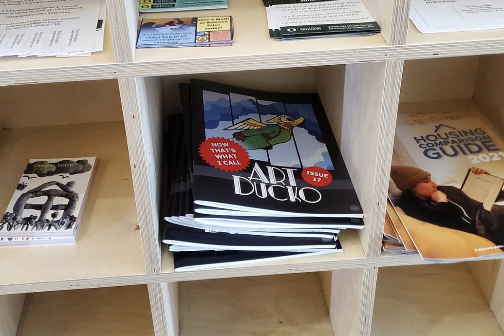 Art Ducko magazines displayed on a bookshelf next to other publications and works.