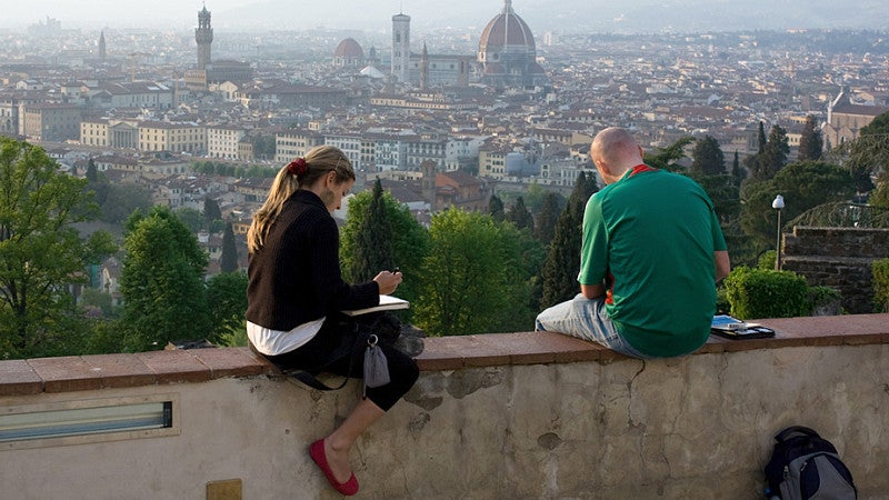 (Two students are sitting and sketching or writing at sunset in Siena, Italy.) Creative Writing in Oviedo