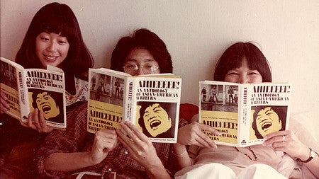 Three students reading copies of Aiiieeeee!: An Anthology of Asian American Writers.