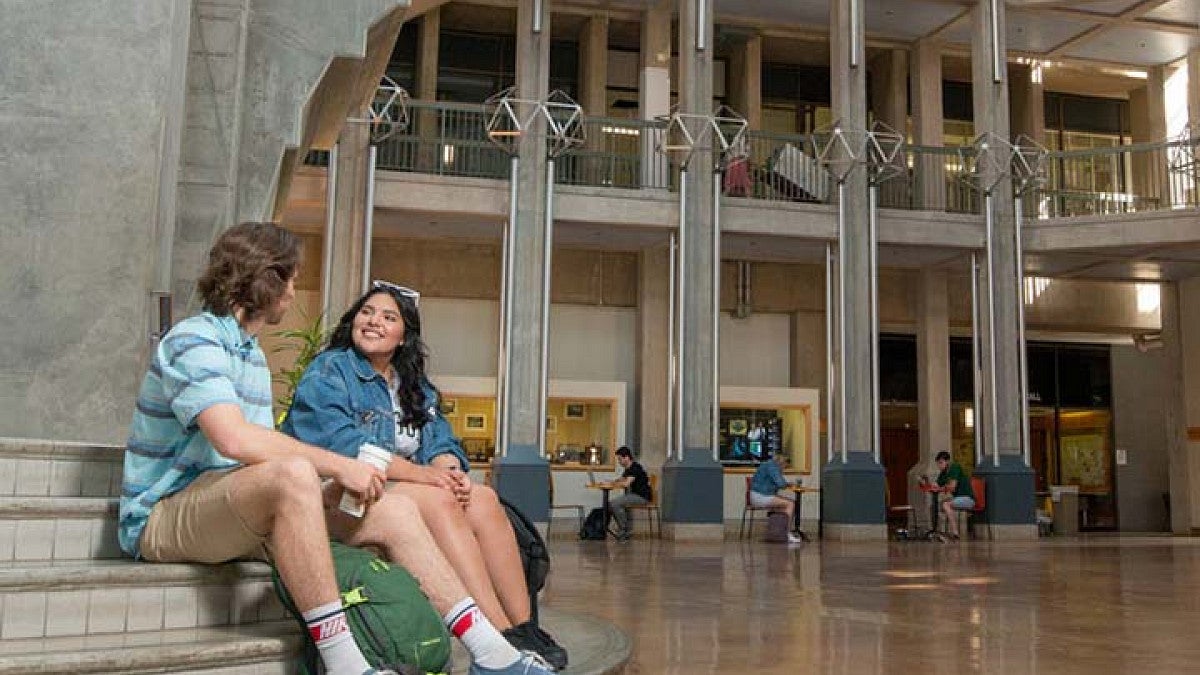 Two students sitting on steps smiling at each other.