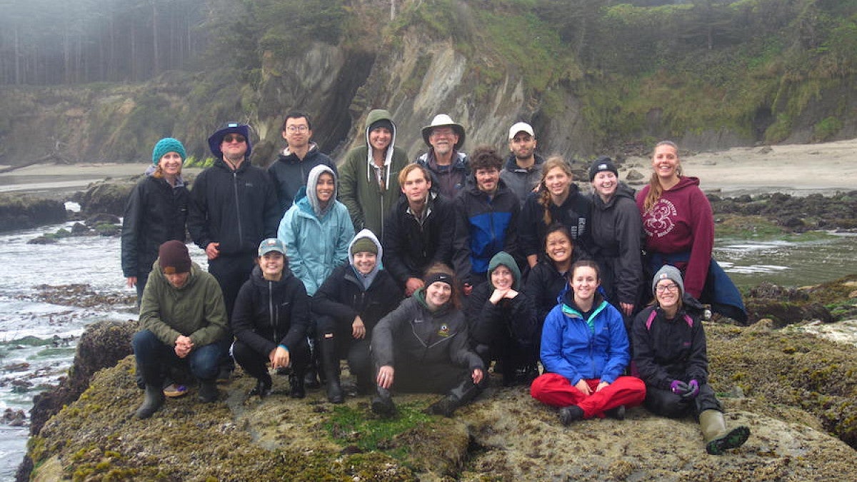 Marine biology student group posing for a photo on a rocky shoreline.