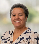 A woman with a floral shirt on and short dark hair 