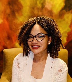 African American woman wearing tortoise shell glasses, smiling.