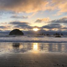 A view of the ocean with the sun setting on the horizon.