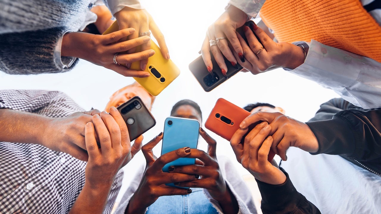 Five people holding smartphones outdoors