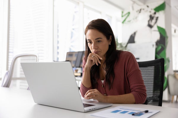 Thoughtful serious woman working at laptop in office