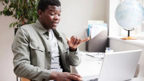 Man using American sign language with laptop