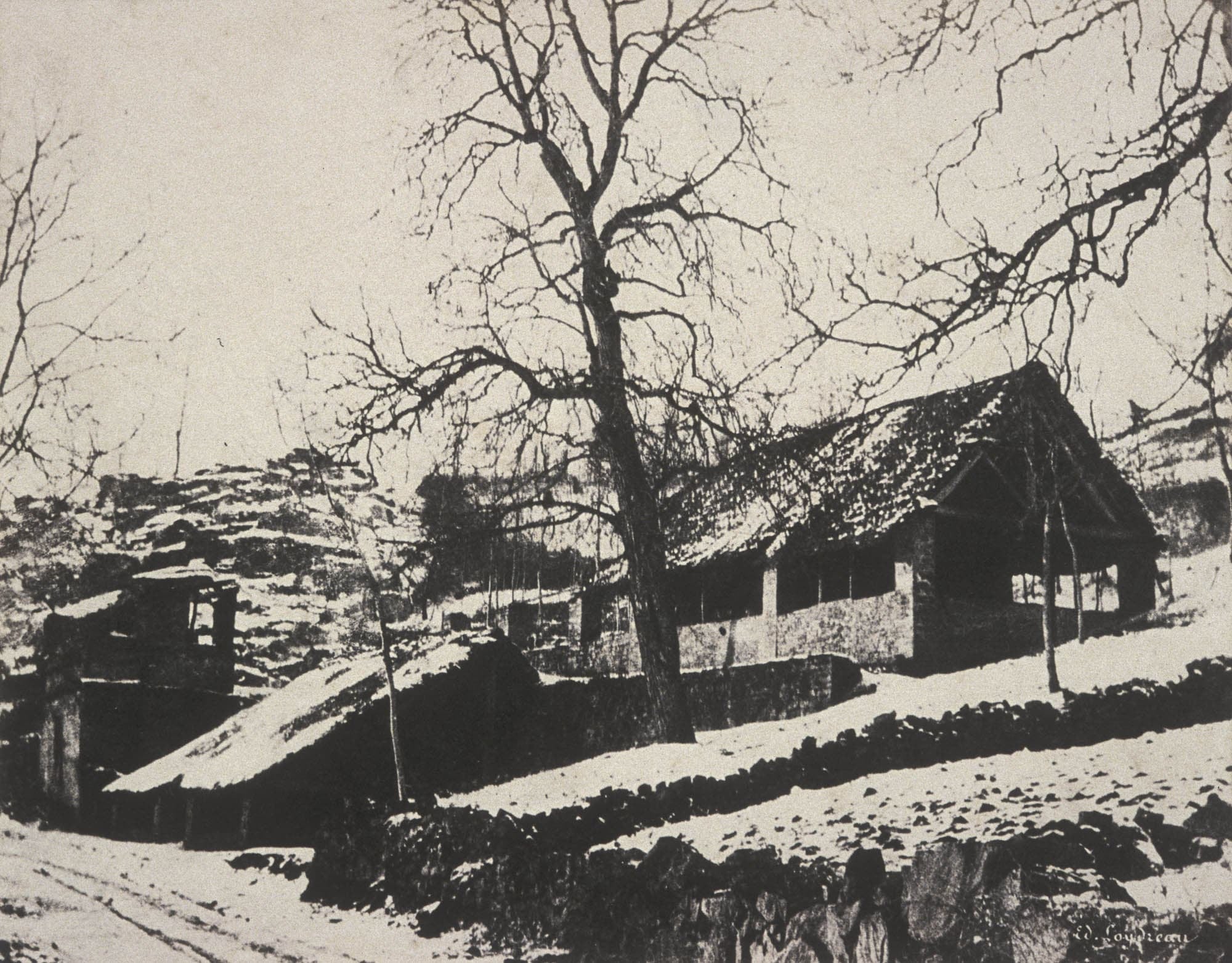 Old black and white photograph of a stone building in the snow viewed from a lower vantage point.