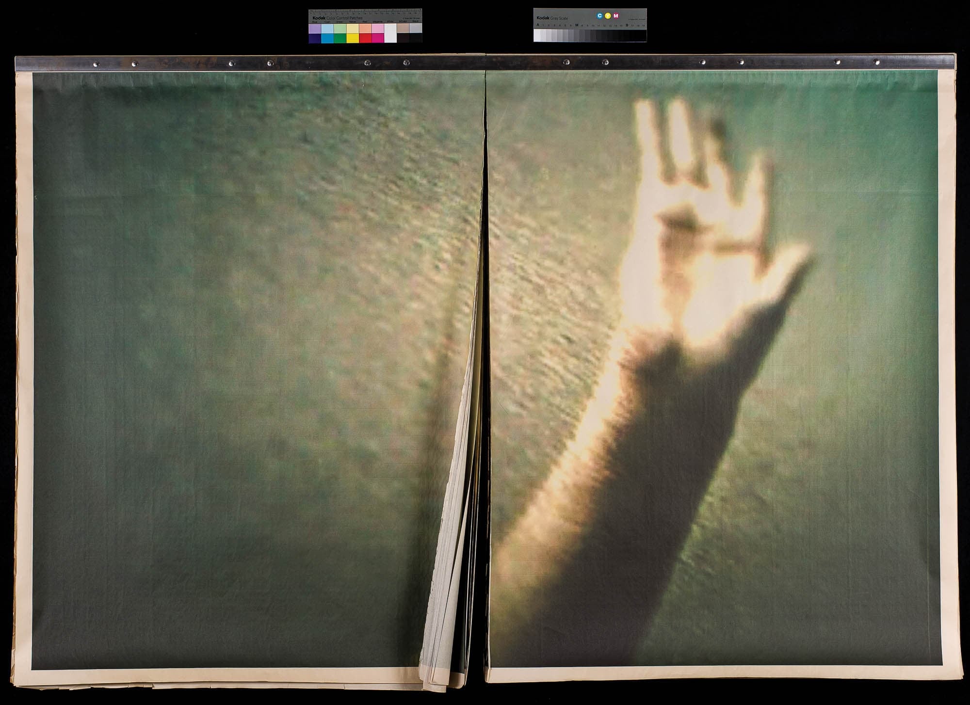 A blurry, enlarged photograph of a hand reaching upwards, displayed across two pages. The out-of-focus effect gives the image an ethereal and mysterious quality.