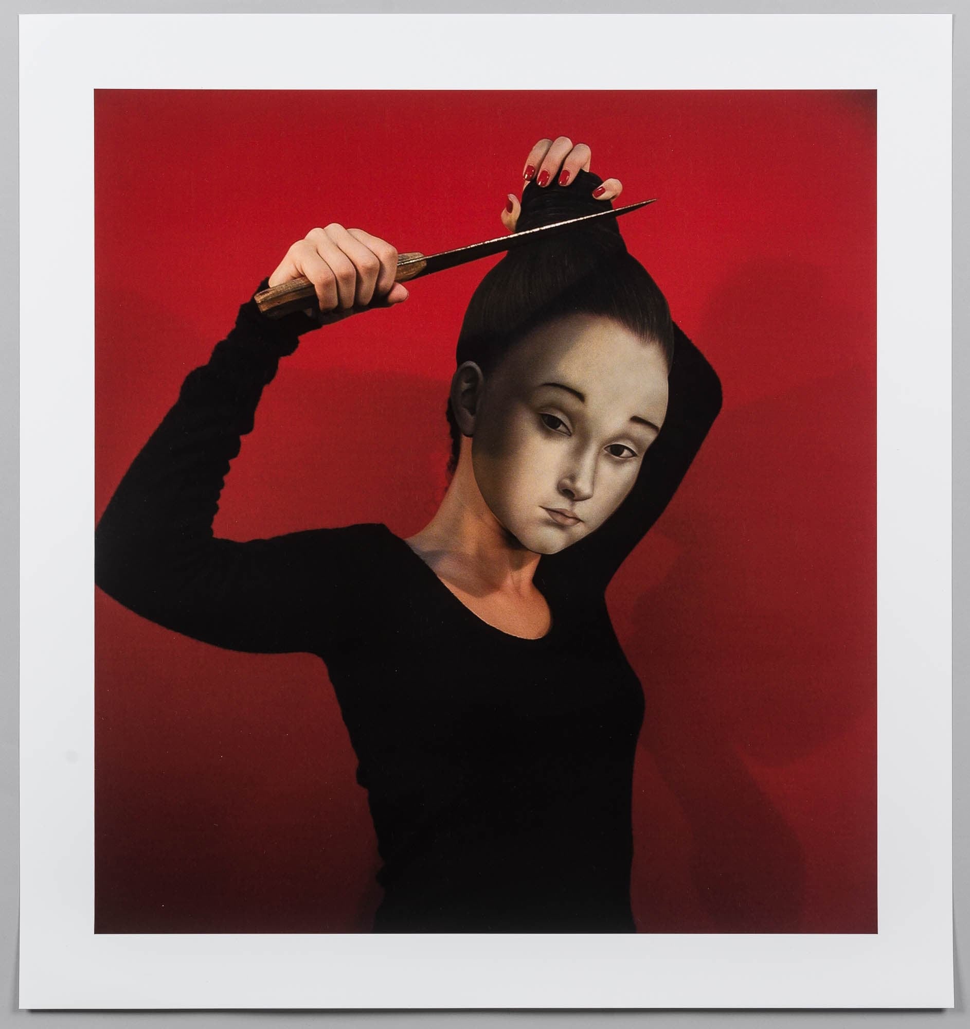A photographic portrait of a young girl in a black outfit, styling her hair with a knife against a vivid red background. The juxtaposition of the innocent and the dangerous creates a striking image.