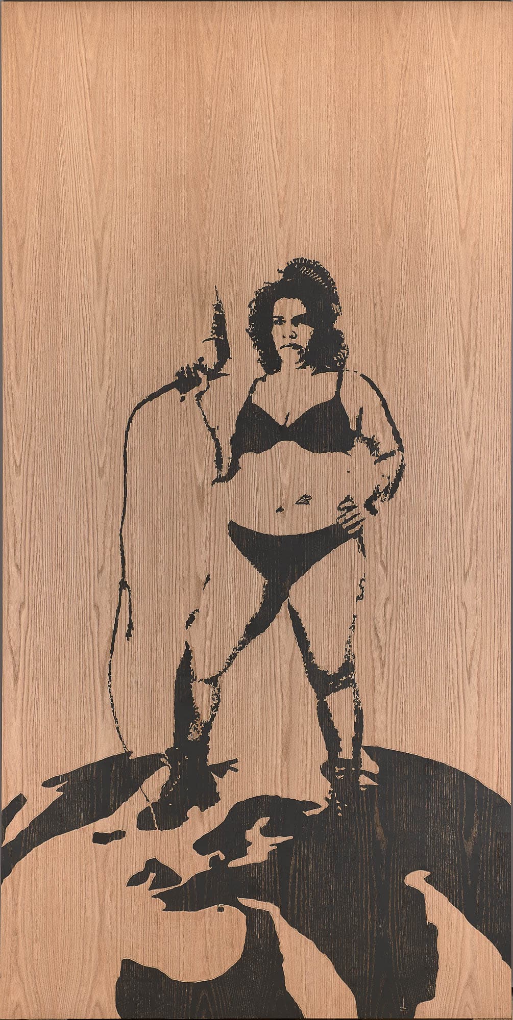 A large wood panel with an image of a woman in a bikini holding a power tool. The black ink illustration contrasts with the natural wood grain, creating a bold visual statement.
