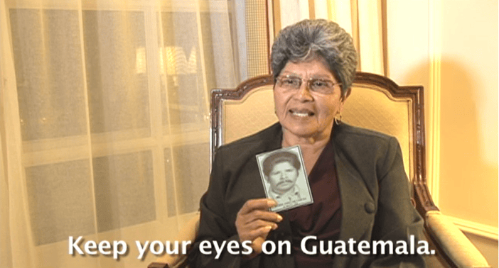 Woman sits in a chari holding a bkack and white photos of a man who is missing.