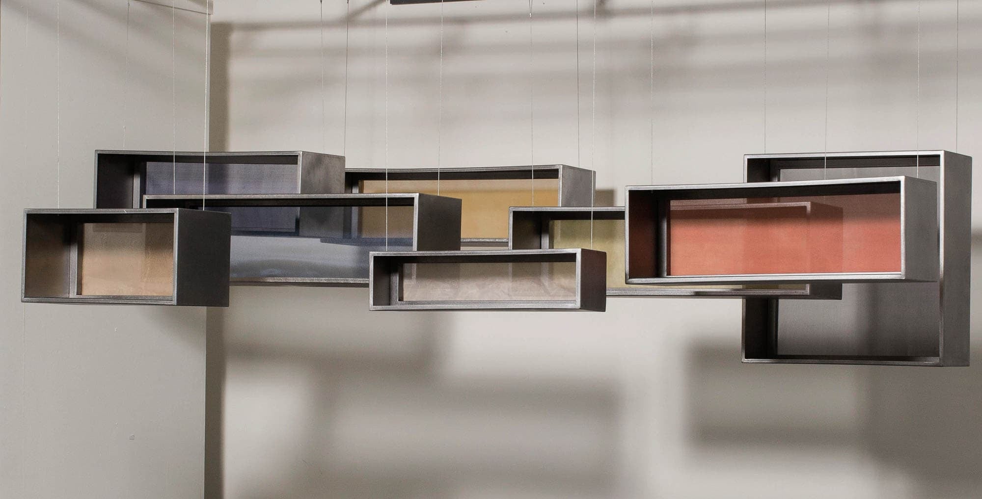 A modern art installation consisting of several metal boxes hanging in the air, creating an abstract geometric composition.