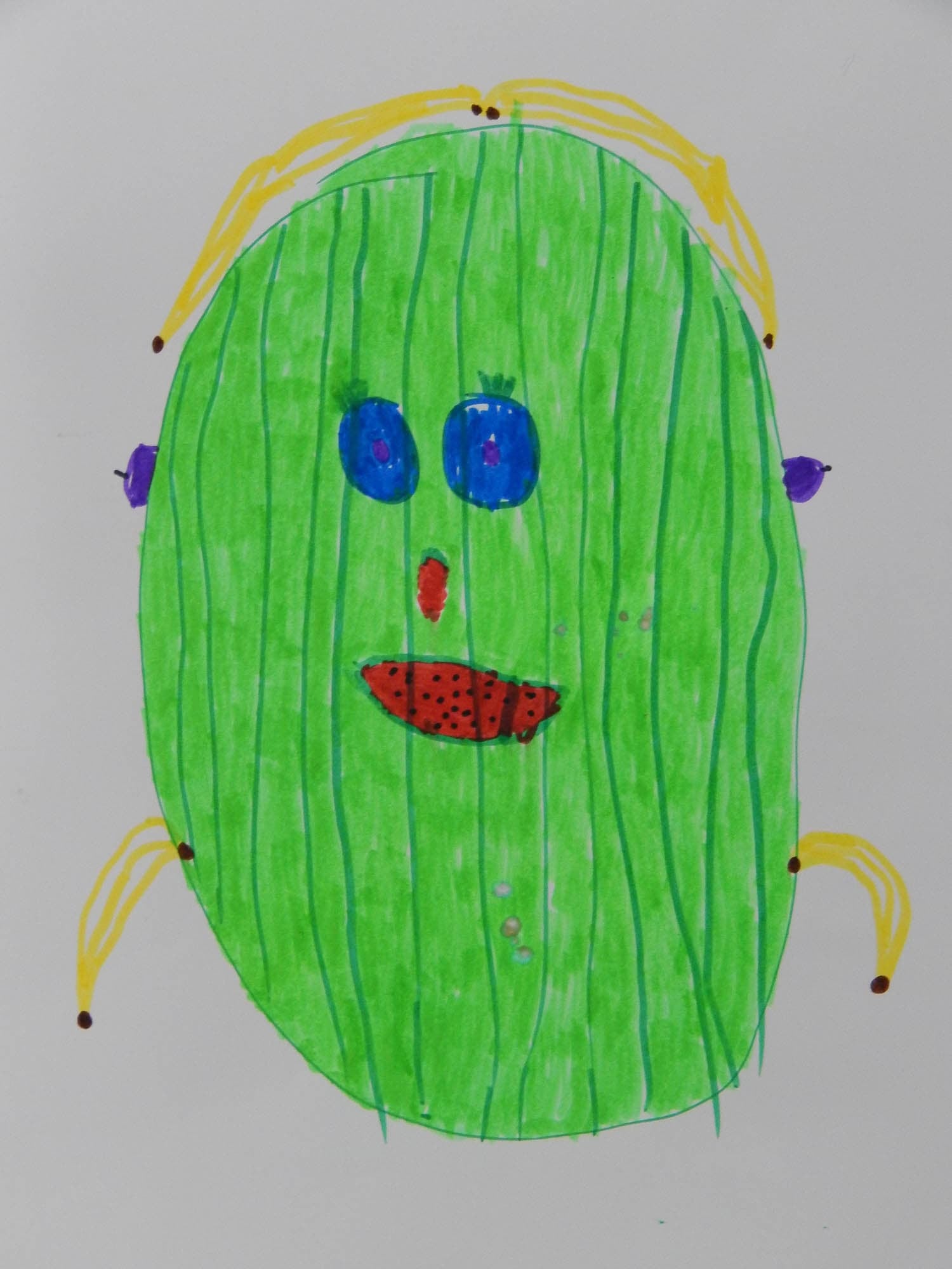 A child's drawing of an oval-shaped green face with blue eyes, yellow hair, and a red mouth with black dots, exuding a whimsical character.