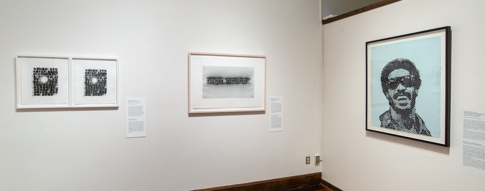 Gallery view showing three framed prints, two in black and white and one with a light blue background and a dot pattern image of a laughing man wearing sunglasses.