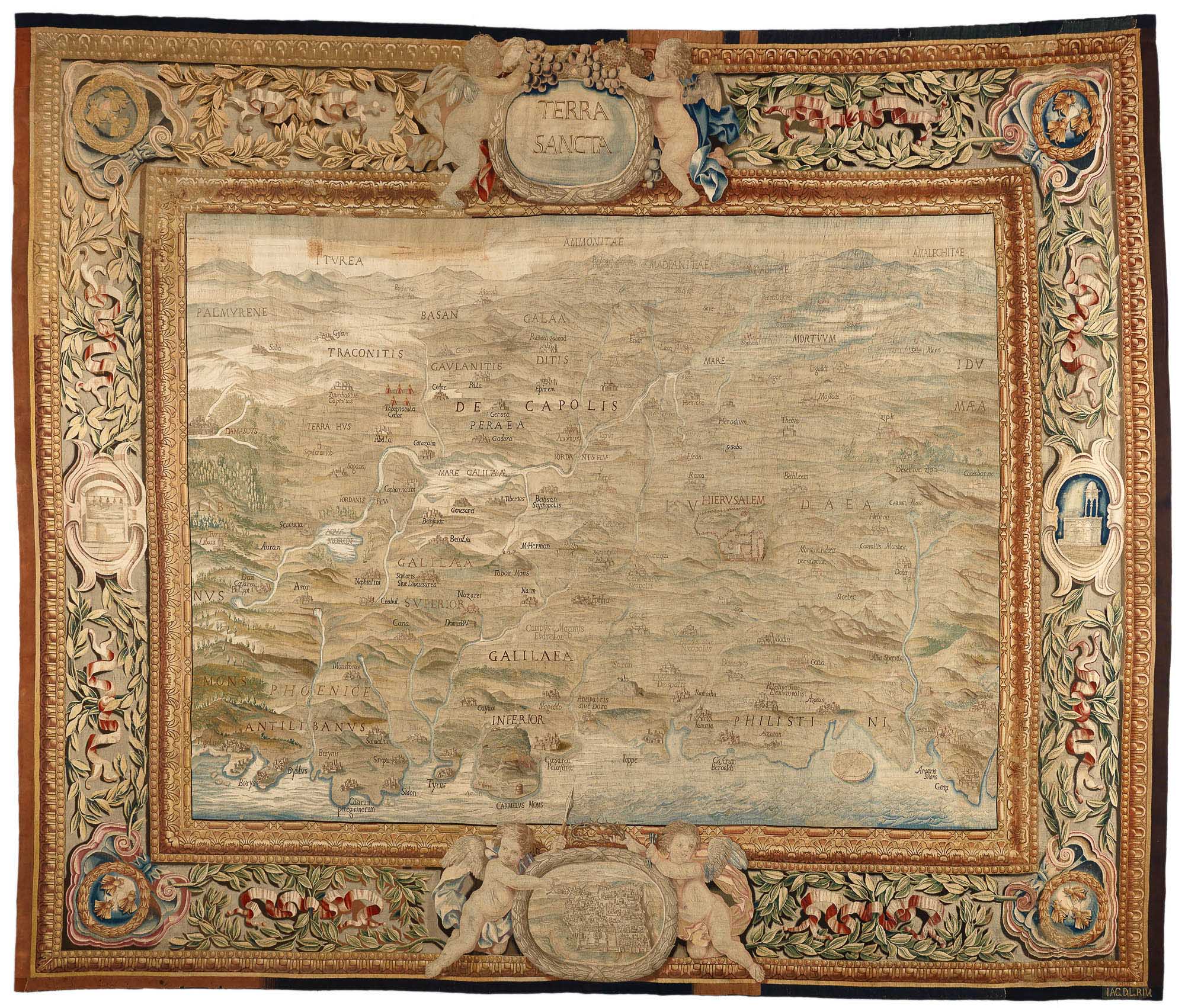 An antique tapestry map titled "Terra Sancta," decorated with intricate borders featuring cherubs and floral patterns. The map details regions with labeled cities and topographical features.