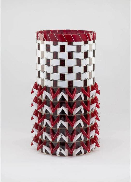 Sculpture made from film strips, forming a cylindrical shape with red and white triangular patterns.