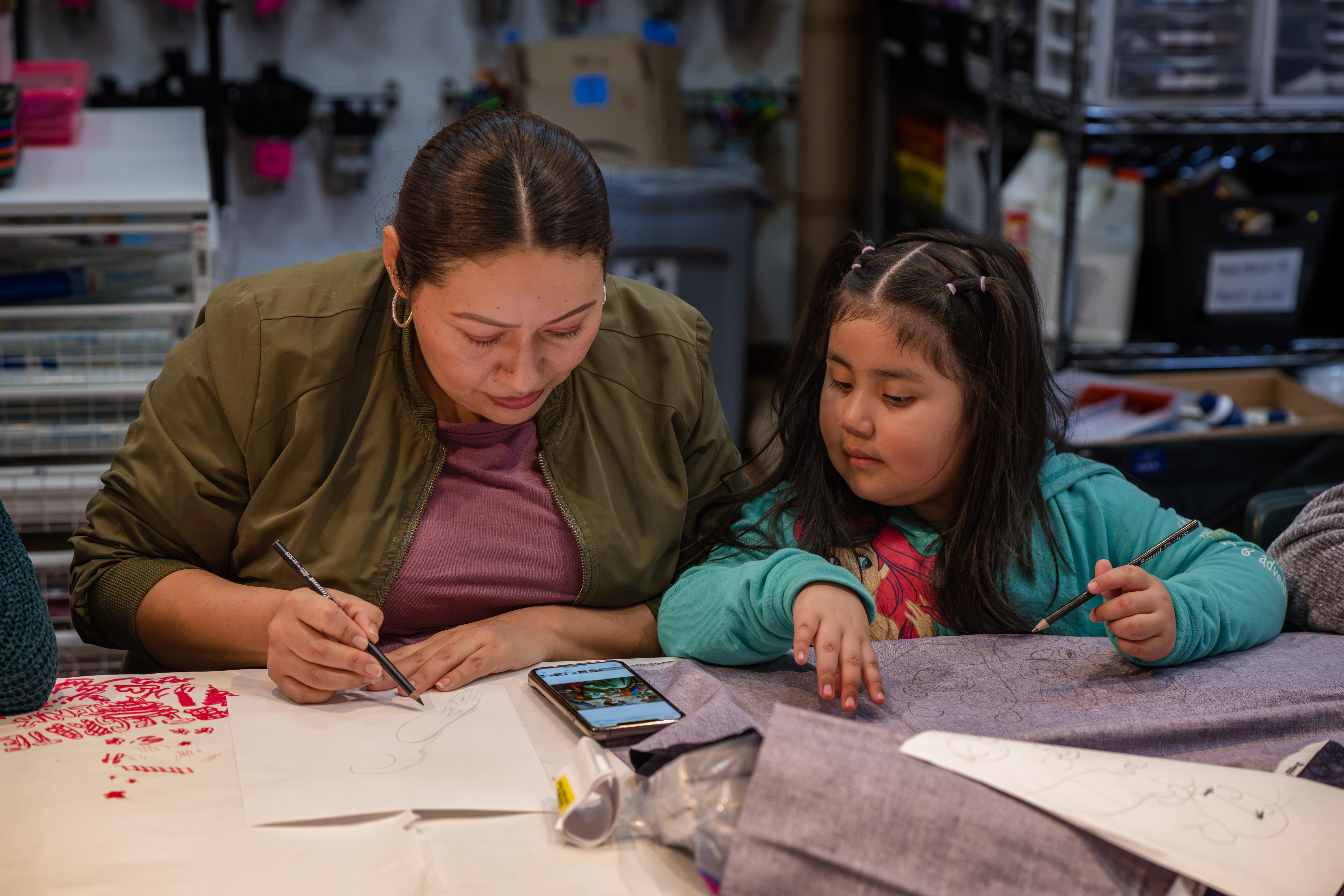 Mother and daughter sit at a table creating art.