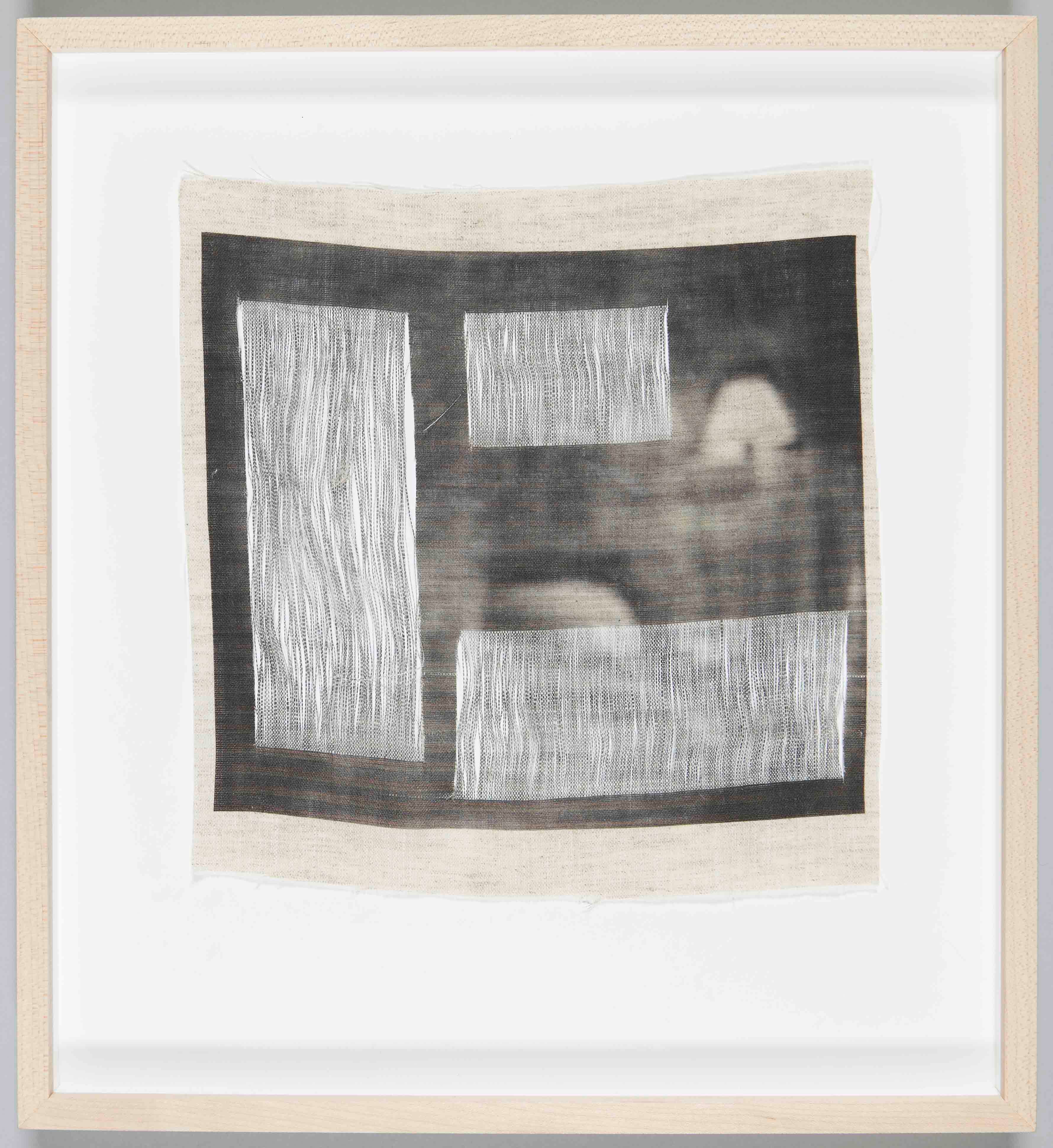 Fabric artwork in a light wood frame. The artwork is a series of white rectangles on a black background.