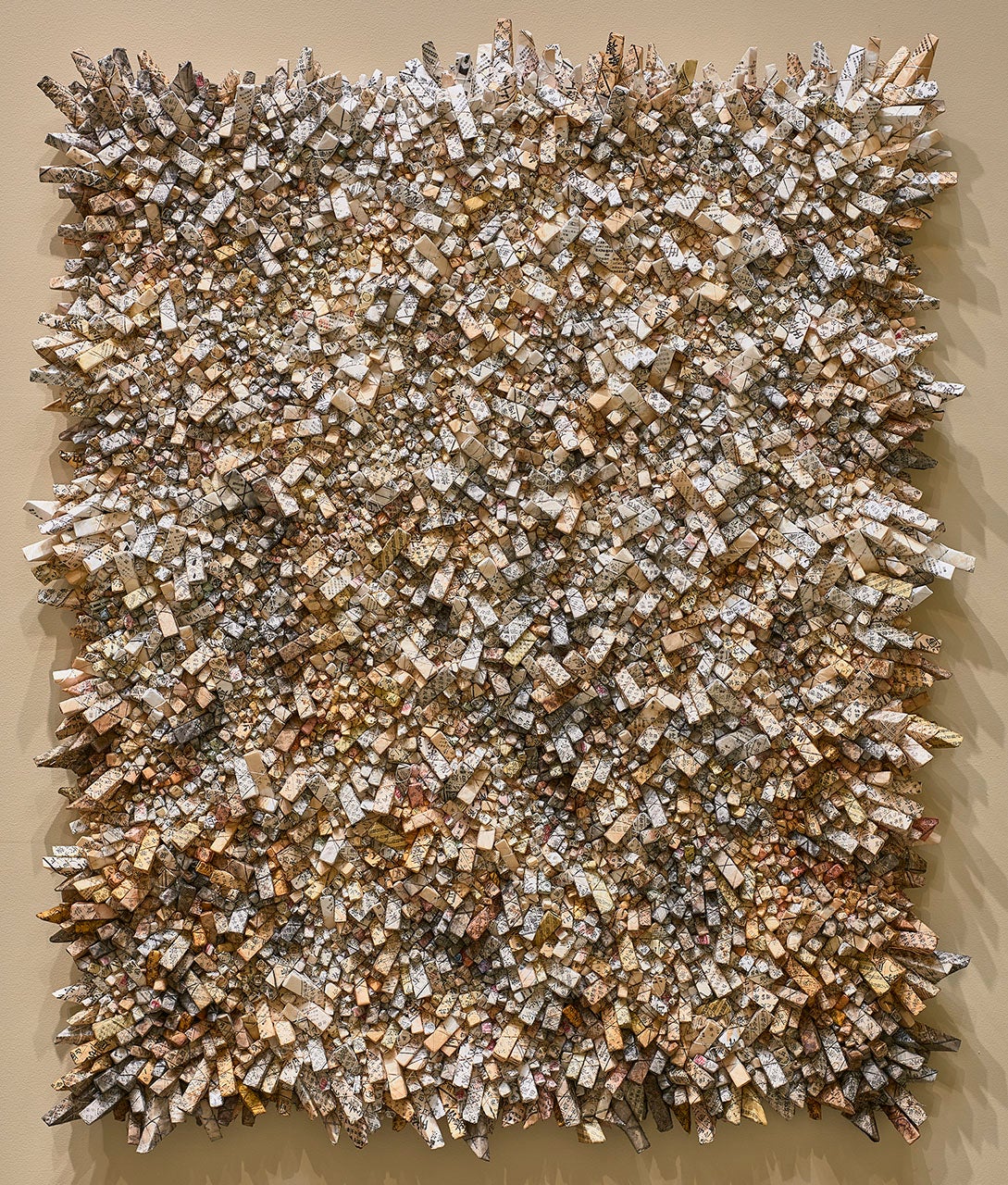 An abstract artwork of a field of paper constructions sticking out of the wall.